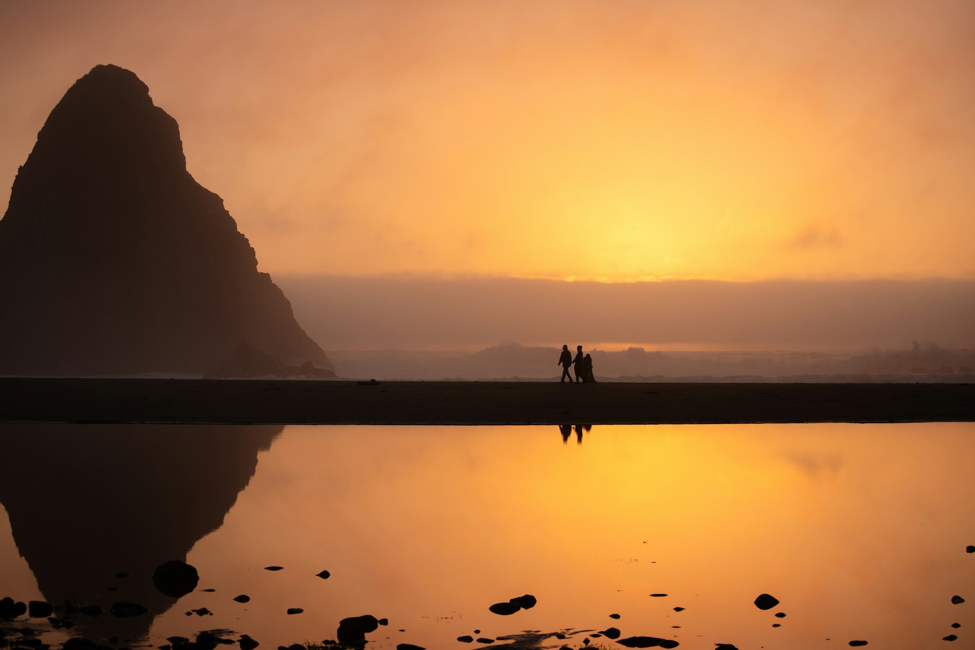 Couple walking along beach at a distance during golden hour